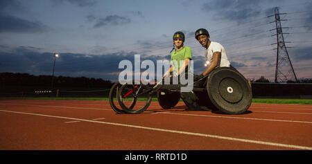 Ritratto fiduciosi, paraplegico atleti sulla via dello sport, corsi di formazione per una sedia a rotelle gara in notturna Foto Stock