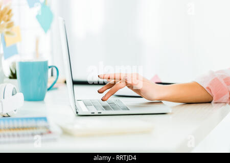 Vista parziale di donna digitando sulla tastiera portatile al lavoro Foto Stock