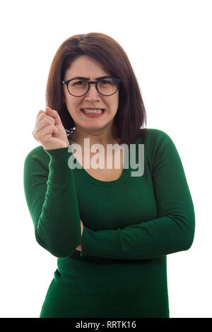 Adirato contro la donna che mostra i denti e il pugno di contenimento cercando nervoso per fotocamera indossando occhiali isolate su sfondo bianco. Giovane insegnante infastiditi scolding Foto Stock