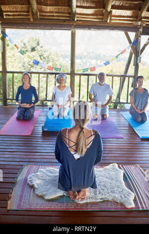 Donna che conduce alla meditazione nella capanna durante il ritiro di yoga Foto Stock