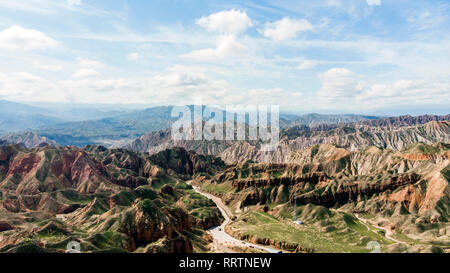 Vista aerea di Danxia Binggou Canyon rilievi in Zhangye, Sunan Regione, Provincia di Gansu, Cina. Sharp picchi appuntiti nel Geoparco. Strada a valle su un Foto Stock