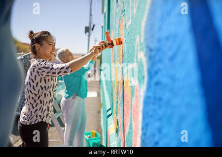 Le donne di pittura murale vibrante sulla soleggiata parete urbana Foto Stock