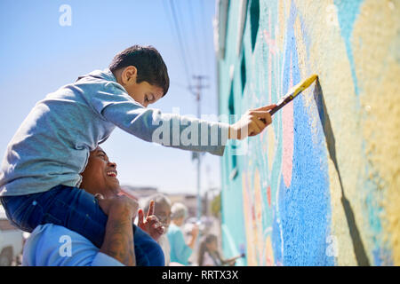 Padre e figlio volontari pittura murale sulla parete soleggiato Foto Stock