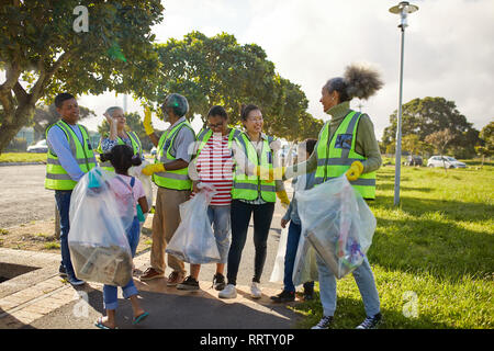 Felice volontari celebrando, pulizia figliata da soleggiato parco Foto Stock