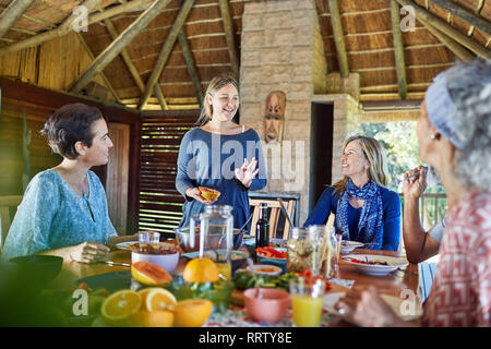 Gli amici sorseggiando una sana prima colazione nella capanna durante il ritiro di yoga Foto Stock