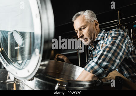 Professional senior brewer in tute da lavoro ispezione Birreria Attrezzature Foto Stock