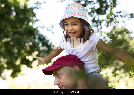 Felice e spensierato ragazza sul padre di spalle Foto Stock