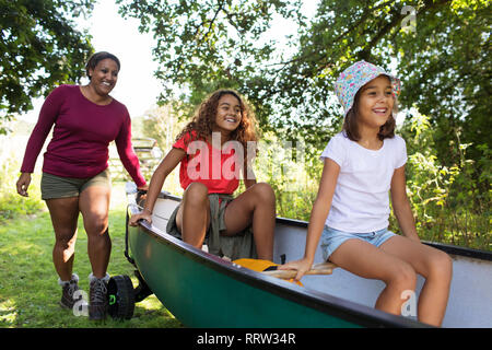 Felice la madre e le figlie spingendo la canoa nei boschi Foto Stock