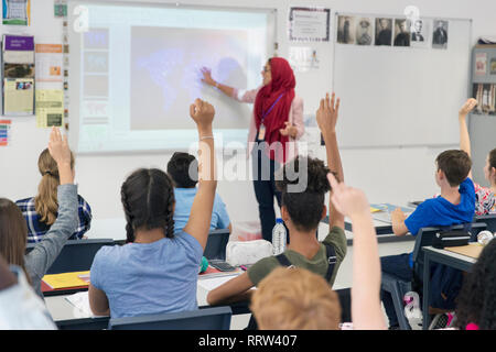 Insegnante femminile in hijab insegnamento lezione a schermo di proiezione in aula Foto Stock