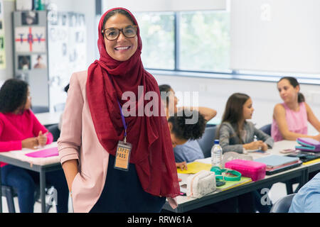 Ritratto sorridente e fiducioso insegnante femminile di indossare il hijab in aula Foto Stock