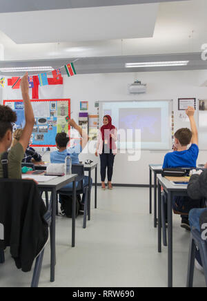 Insegnante femminile in hijab rispondendo alle domande degli studenti in aula Foto Stock