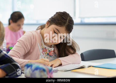 Focalizzato junior high school girl studente facendo i compiti in classe Foto Stock