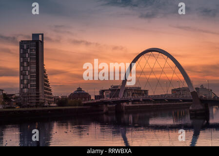 Glasgow/SCOZIA - 20 Settembre 2016: il Clyde Arc e degli edifici circostanti contro un arancione tramonto sul fiume Clyde Foto Stock