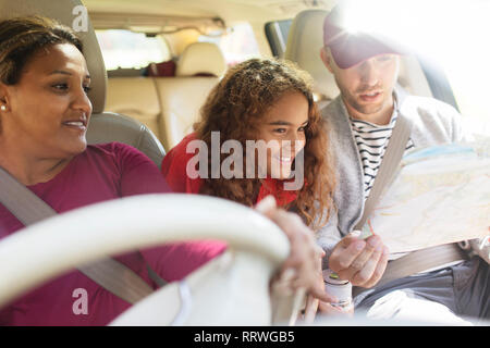 Famiglia con mappa di equitazione in auto in viaggio Foto Stock