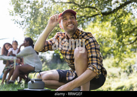 Uomo felice teiera di riscaldamento sul fornello da campeggio Foto Stock