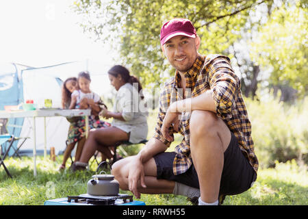 Ritratto fiducioso uomo teiera di riscaldamento sul fornello da campeggio a sunny campeggio Foto Stock