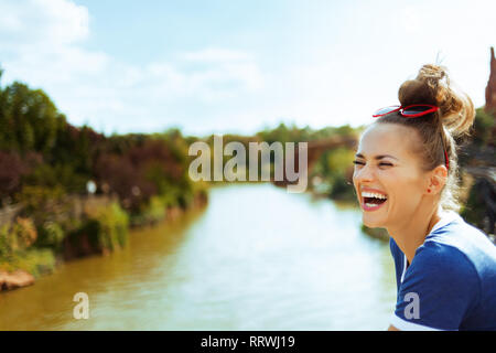 Sorridente donna sana in maglietta blu sulla barca fluviale avente tempo di divertimento durante la crociera fluviale. Foto Stock