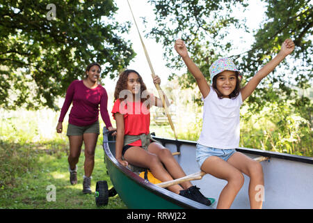 Felice la madre e le figlie spingendo la canoa nei boschi Foto Stock