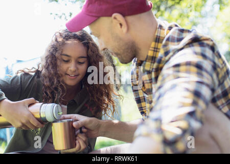 Figlia versando caffè isolato dal contenitore per bevande per il padre Foto Stock