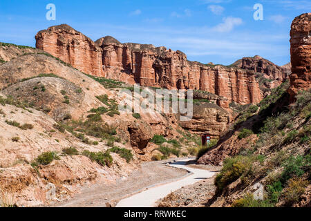 Il percorso in Valle di Danxia Binggou Canyon rilievi in Zhangye, Sunan Regione, Provincia di Gansu, Cina. Pietra arenaria rossa rocce del Geoparco. Pietre Rosse. Foto Stock