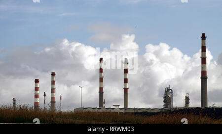 Parte di una grande raffineria di petrolio con il rosso e bianco camino in una mattina nuvoloso Foto Stock