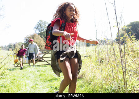 Felice ragazza con zaino camping, in esecuzione nel campo di sole Foto Stock