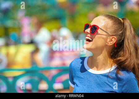 Sorridente viaggiatore sano donna in blu t-shirt in parco divertimenti avente tempo di divertimento. Foto Stock