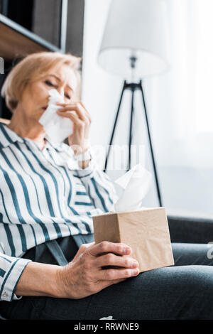 Malati senior donna con naso che cola soffrono di freddo ed il trattenimento del tessuto box a casa Foto Stock