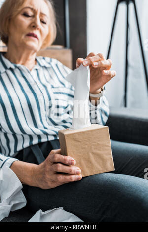 Malati senior donna soffrono di freddo e per raggiungere il tessuto mentre seduti a casa Foto Stock