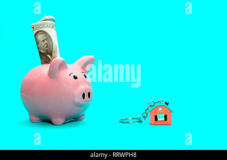 Rosa salvadanaio con una casa sul tavolo. Oscurata. Concetto di salvataggio di finanze e real estate depositi Foto Stock
