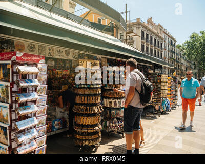 Barcellona, Spagna - 1 GIU 2018: uomo sulla Rambla di Barcellona centrale con i punti shopping vendita di souvenir diversificato - cartoline, magneti, Foto Stock