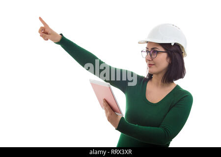 Allegro giovane donna ingegnere indossare casco protettivo e bicchieri utilizzando un computer tablet gadget puntare il dito indice che mostra fino isolate su whit Foto Stock