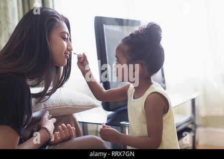 Carino il toddler girl applicando lip gloss per labbra sorelle Foto Stock