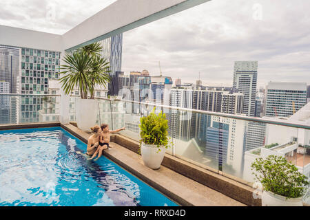 La madre e il figlio in piscina tra i grattacieli e le grandi città. Potrete rilassarvi nella grande città. Il resto da stress Foto Stock