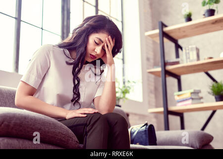 Cupa stanco giovane donna tenendo la fronte Foto Stock