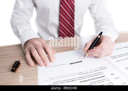 Imprenditore in camicia e cravatta firma un contratto di carta con una penna stilografica su una scrivania Foto Stock