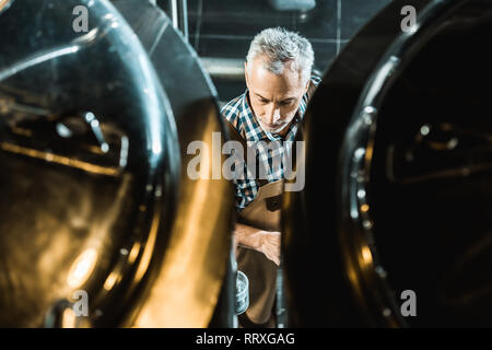 Vista aerea del birraio maschio in tuta da lavoro con birreria attrezzature Foto Stock