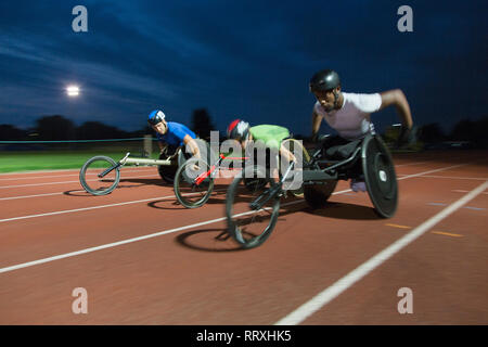 Gli atleti paraplegici racing lungo la via dello sport in carrozzella gara di notte Foto Stock