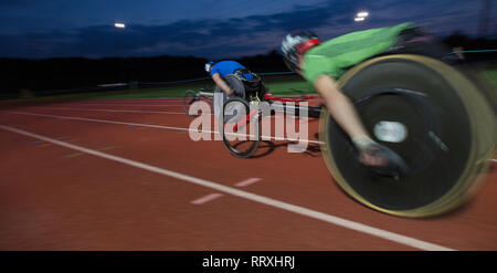 Gli atleti paraplegici accelerando lungo la via dello sport in carrozzella gara in notturna Foto Stock