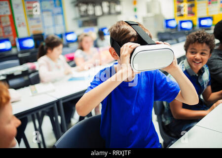 Junior high school boy studente utilizzando la realtà virtuale simulator bicchieri in aula Foto Stock