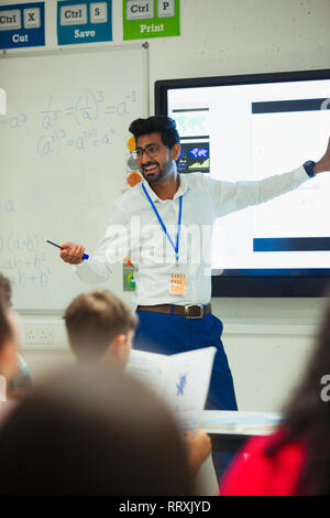 Sorridente insegnante maschio che conduce la lezione in aula Foto Stock