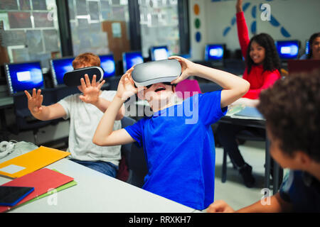 Junior high school boy gli studenti utilizzando la realtà virtuale simulatori in aula Foto Stock