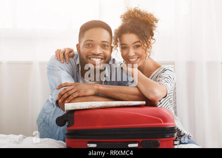 Coppia felice appoggiata sulla valigia, preparazione per le vacanze Foto Stock