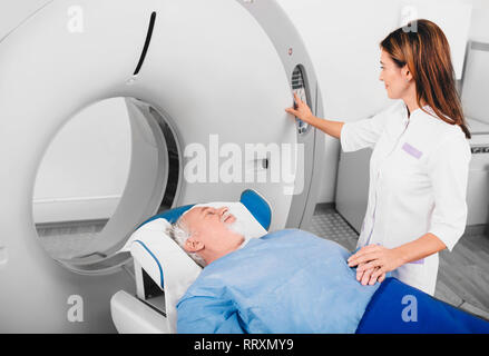 Radiologo rassicurante uomo senior andando in CT scanner in ospedale Foto Stock