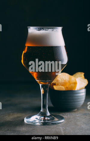 Bicchiere di birra e patatine e scuro dello sfondo grunge Foto Stock