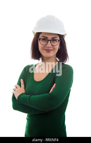 Bella giovane donna ingegnere sorridente positivo con gli occhiali e casco di protezione, tenendo le braccia incrociate, isolato su sfondo bianco. Foto Stock