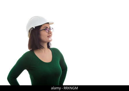 Fiducioso giovane donna ingegnere indossando occhiali e casco di protezione che guarda lontano sorridente isolate su sfondo bianco. Foto Stock