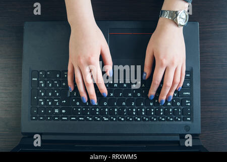 Angolo di alta vista sulla donna con le mani in mano la digitazione sulla tastiera del notebook Foto Stock