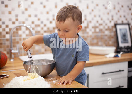 Little Boy preparazione impasto di torta in cucina. Foto Stock