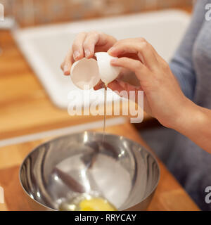 Donna rompere le uova nella piastra di metallo e la preparazione per la realizzazione della torta Foto Stock